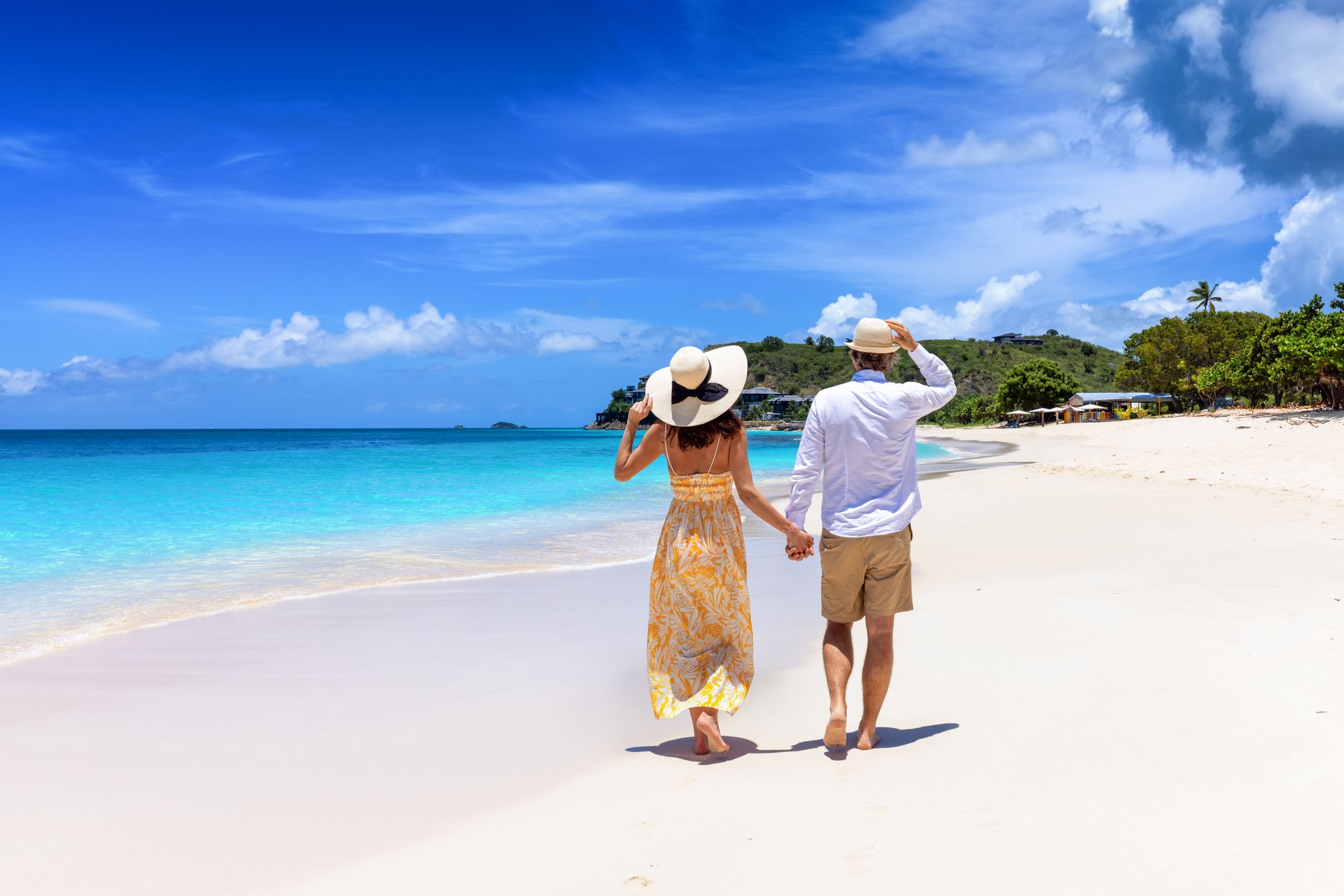 Happy holiday couple walks down a tropical beach in the Caribbean islands